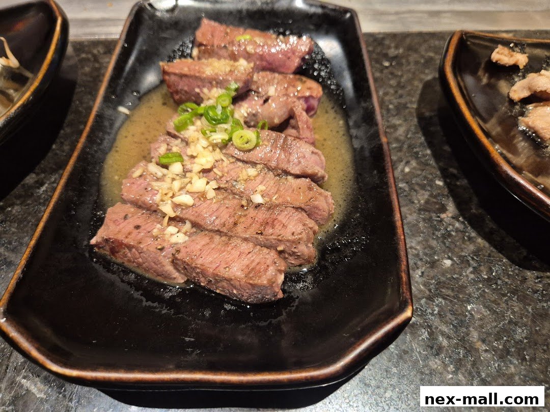 Slices of grilled steak with garlic and green onions on a black plate.