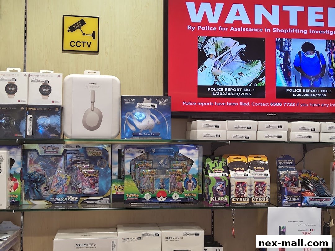 A retail display featuring electronics, collectible trading cards, and a shoplifting warning screen.