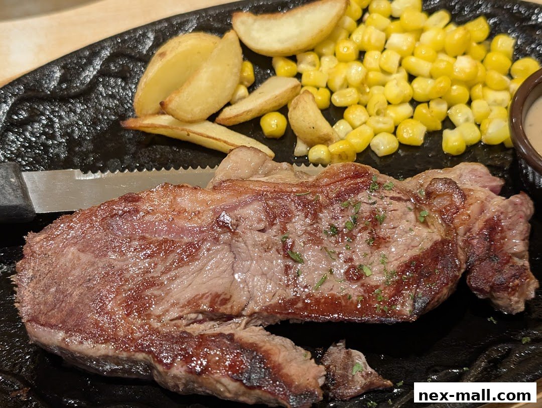 A juicy steak served with corn and potato wedges on a black platter.