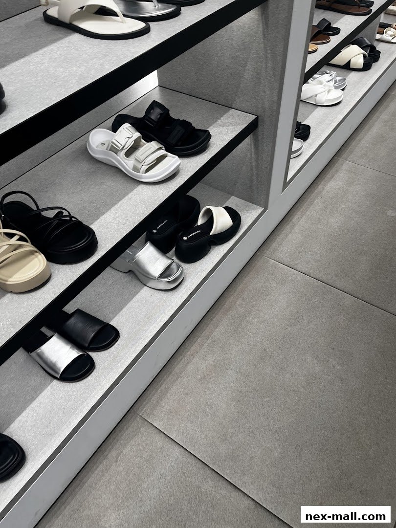 A display of various stylish sandals and slides on shelves in a retail store.