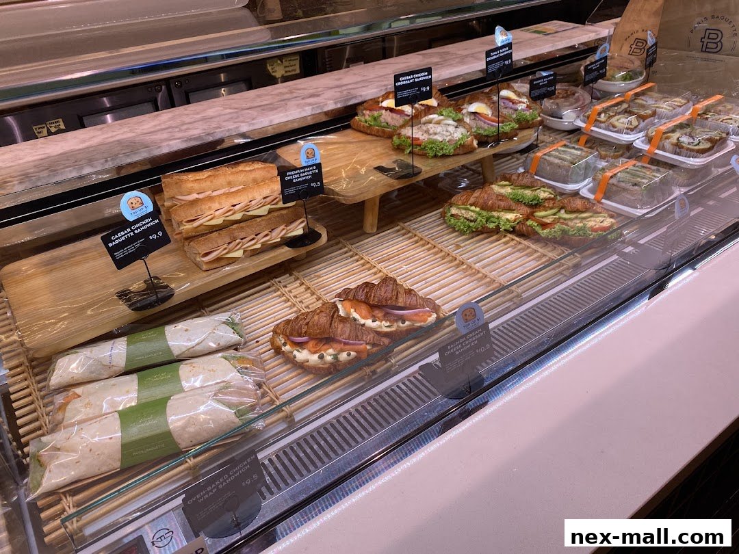 A display case filled with various sandwiches, croissants, and wraps from Paris Baguette.