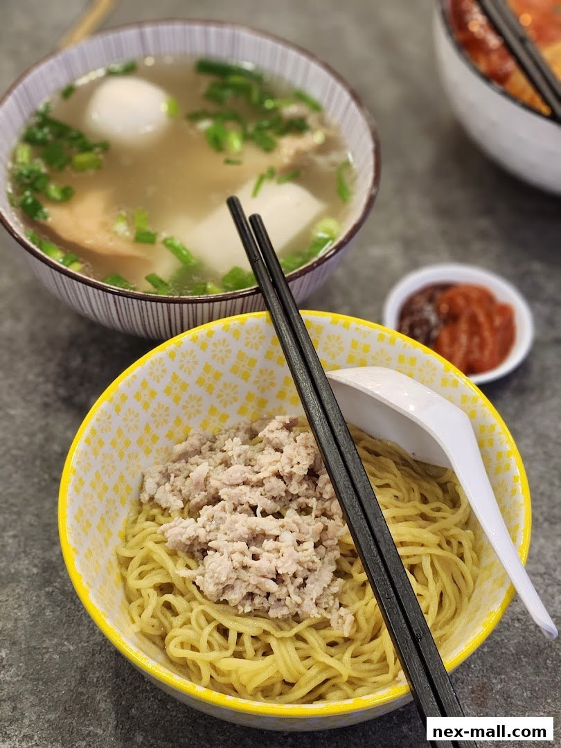A close-up of two bowls of noodles, one with minced meat and the other with soup and fish balls.