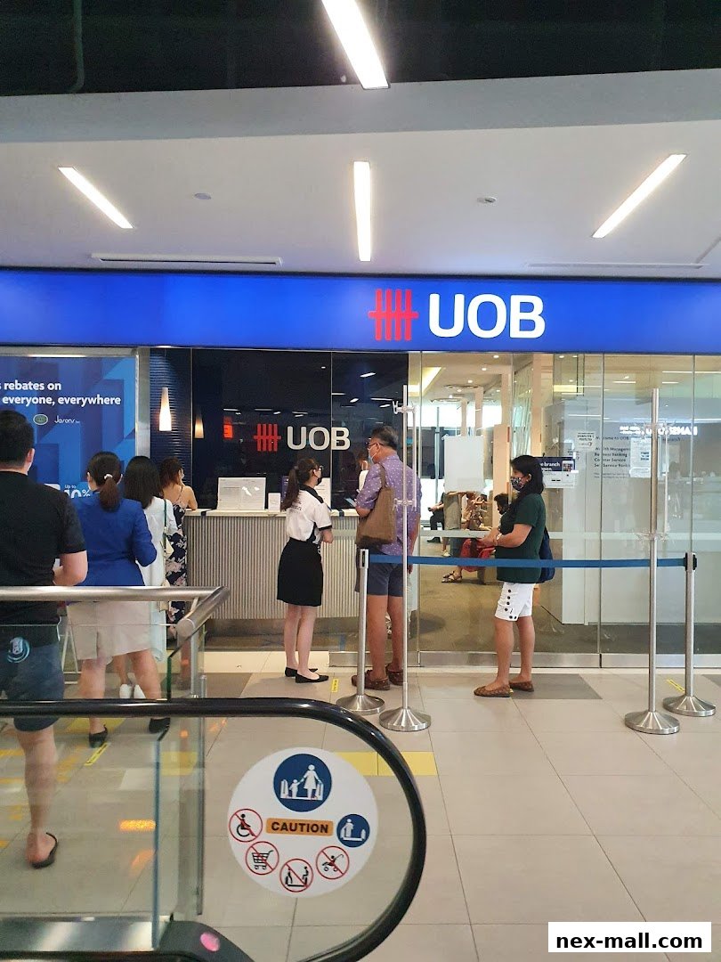 People queuing at the UOB bank branch entrance with clear signage and blue stanchions.