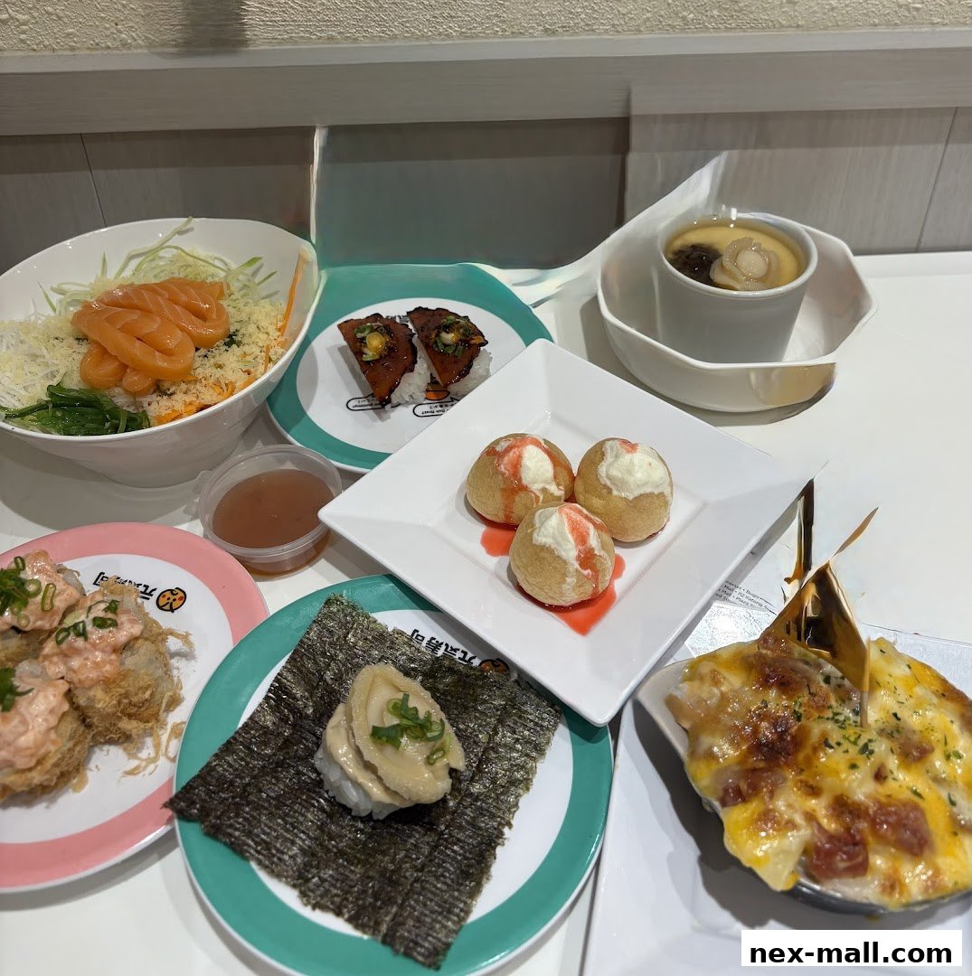 A spread of various sushi dishes and appetizers, including salmon sashimi, baked seafood, and sweet mochi balls.