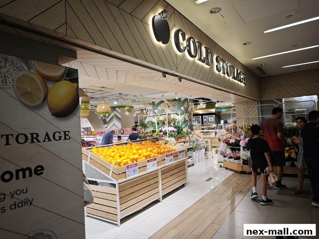 The entrance of a Cold Storage supermarket, showcasing fresh produce and flowers.