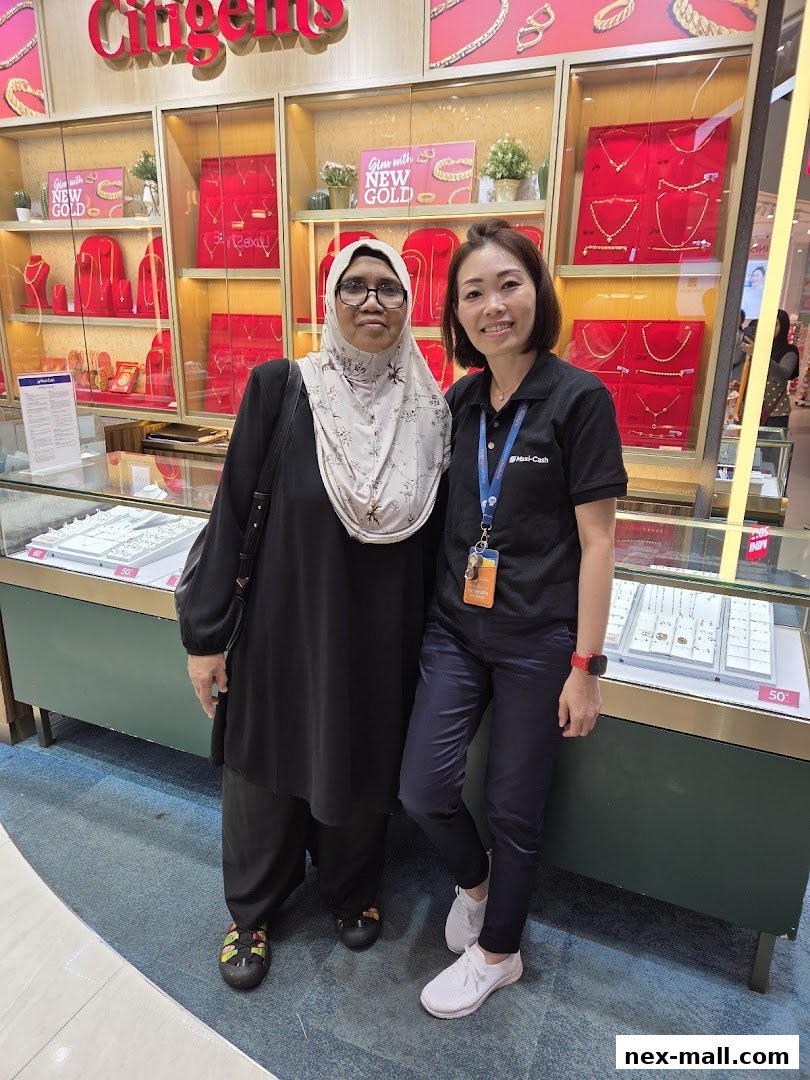 Two women posing in front of a jewelry display at Maxi-Cash.