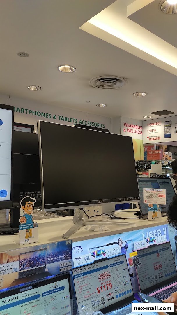 Interior view of Challenger NEX electronics store showcasing monitors and laptops with promotional signage.