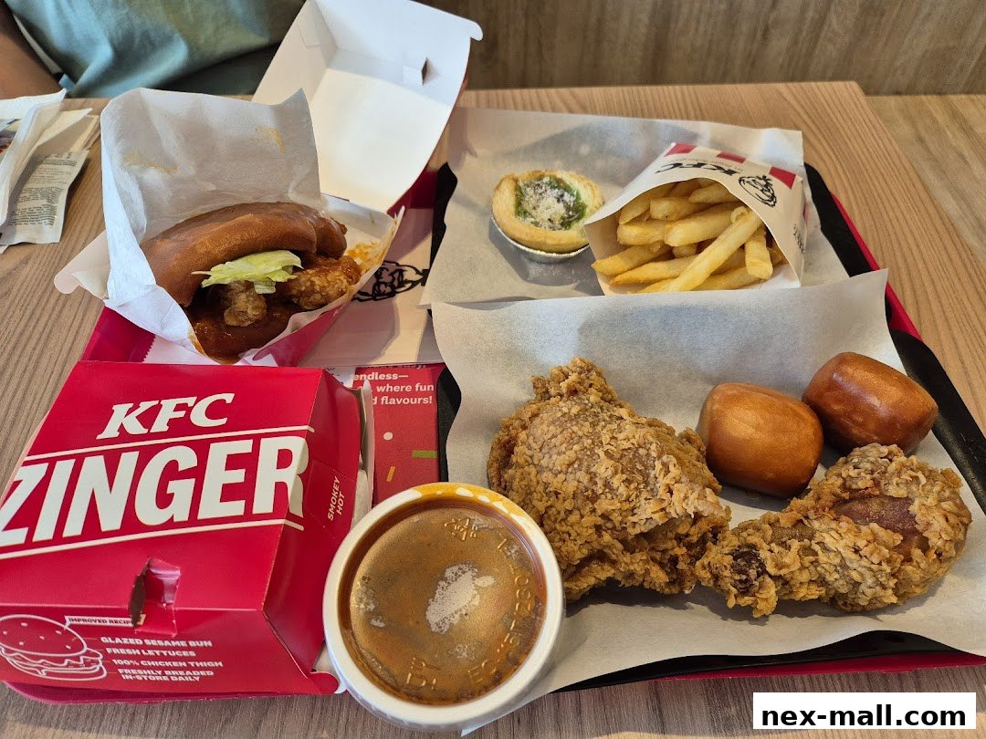 A tray of KFC food including fried chicken, fries, a burger, and sides.