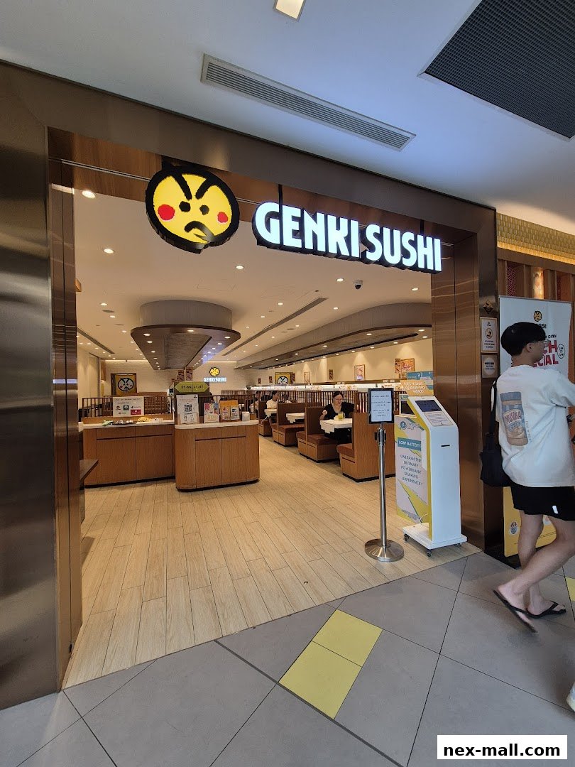 The entrance to Genki Sushi NEX, showing the restaurant interior and a customer walking by.