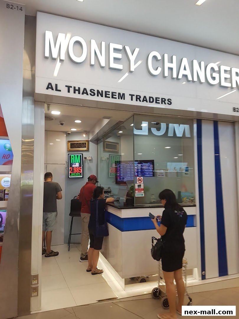 People at the counter of AL Thasneem Traders Money Changer with currency exchange rates displayed.