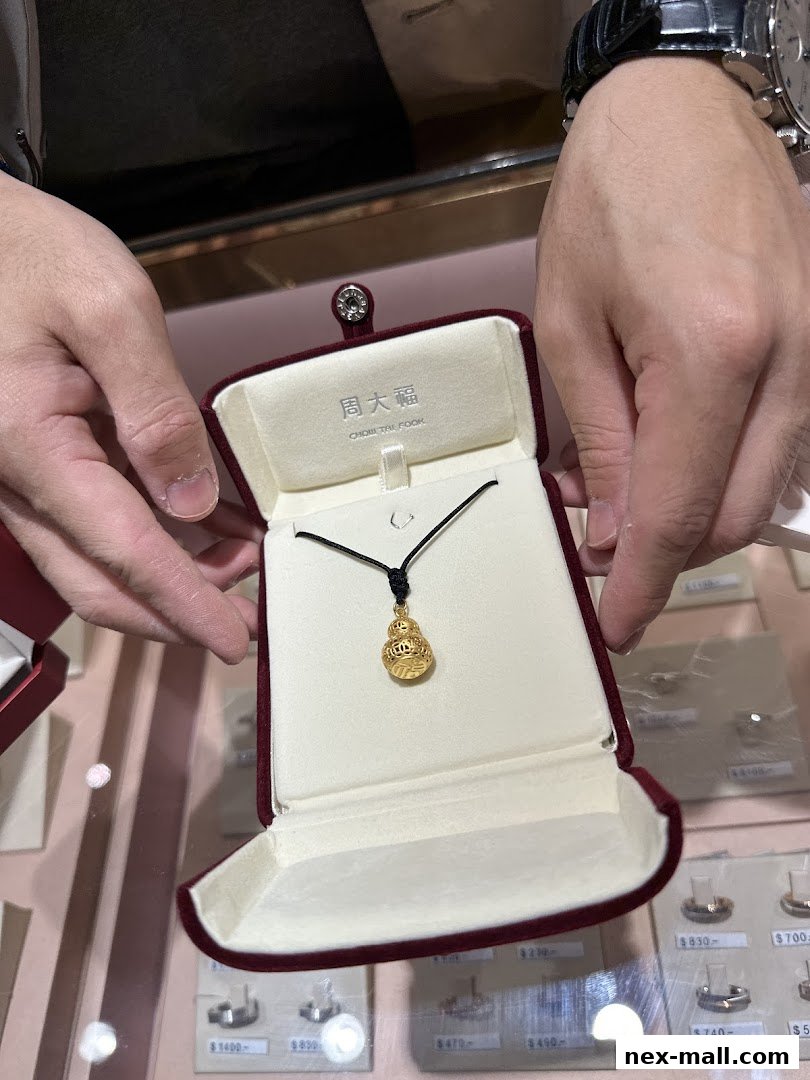 A person holds a gold pendant necklace in a jewelry box at Chow Tai Fook.
