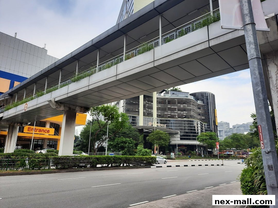 Exterior view of a modern building with a skywalk and an orange 'Entrance' sign.