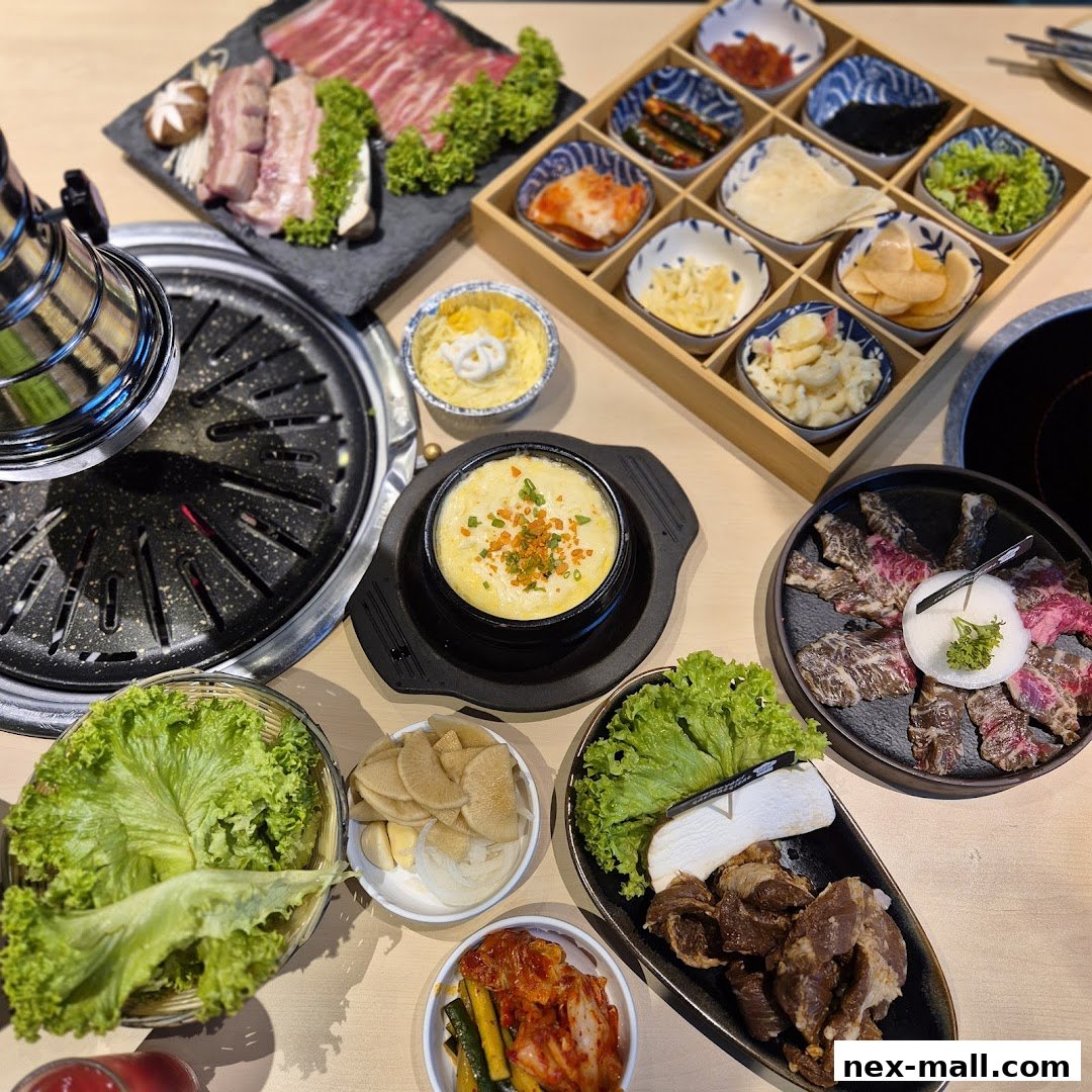 A table laden with Korean BBQ dishes, including raw meats, banchan, and steamed egg.