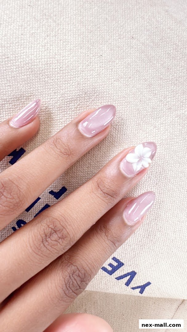 Close-up of a hand with elegant, sheer pink gel nails, one adorned with a delicate white flower.