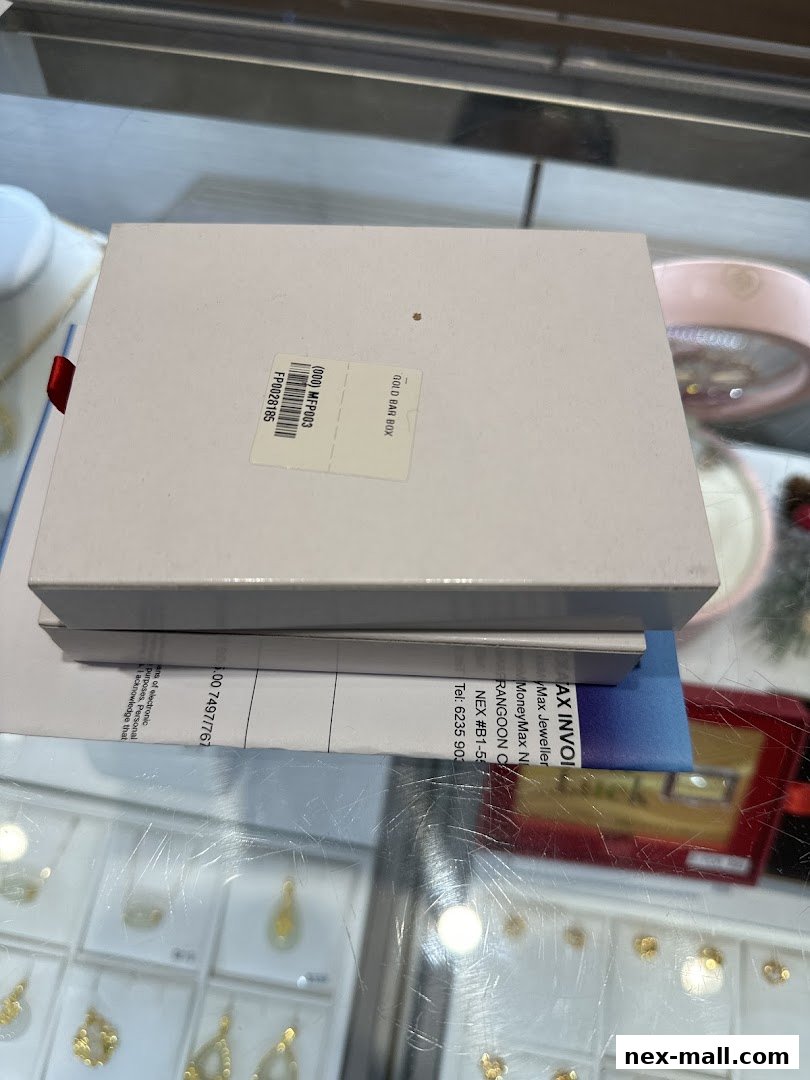 A white box labeled 'GOLD BAR BOX' sits on top of invoices at a jewelry store counter.