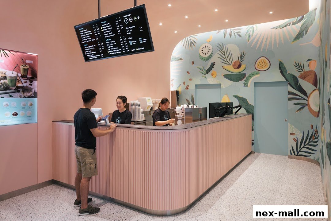 Customers interact with staff at a modern beverage shop counter with a digital menu.