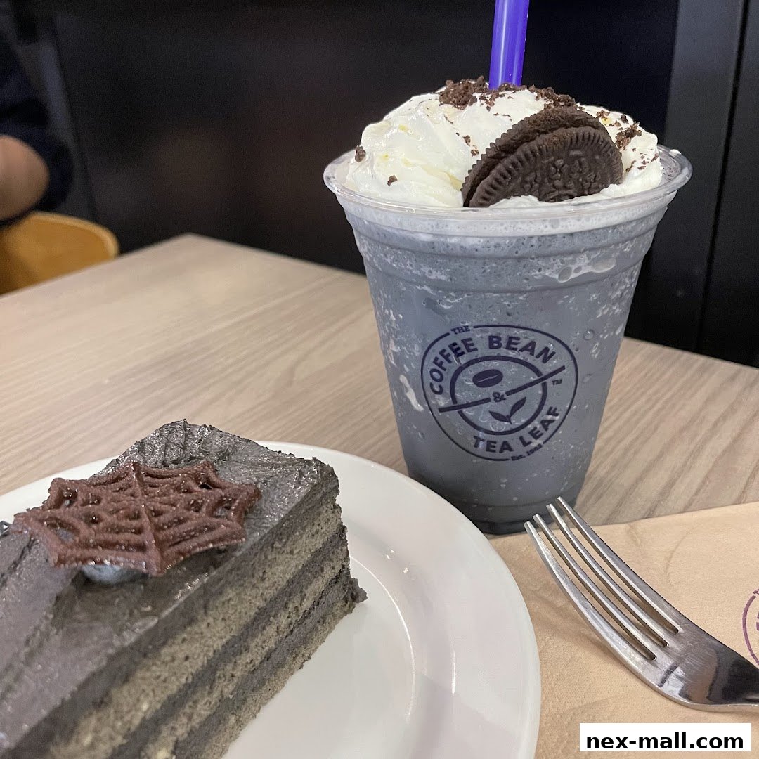 A slice of black sesame cake with a chocolate spiderweb and a blended drink with whipped cream and an Oreo.