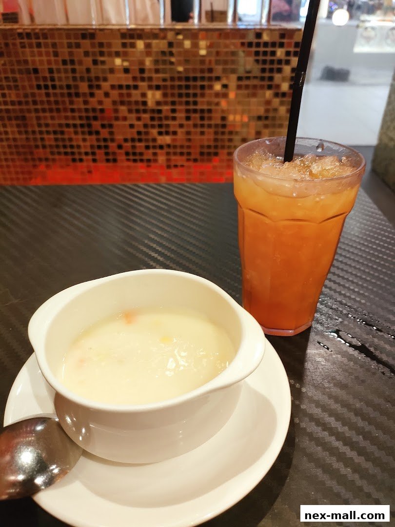 A bowl of creamy soup and a glass of iced tea on a table.