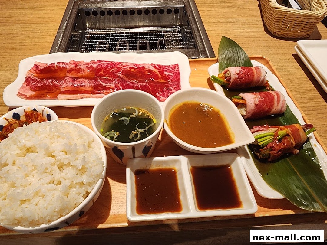 A delicious spread of thinly sliced raw beef, rice, soup, and meat rolls with vegetables.