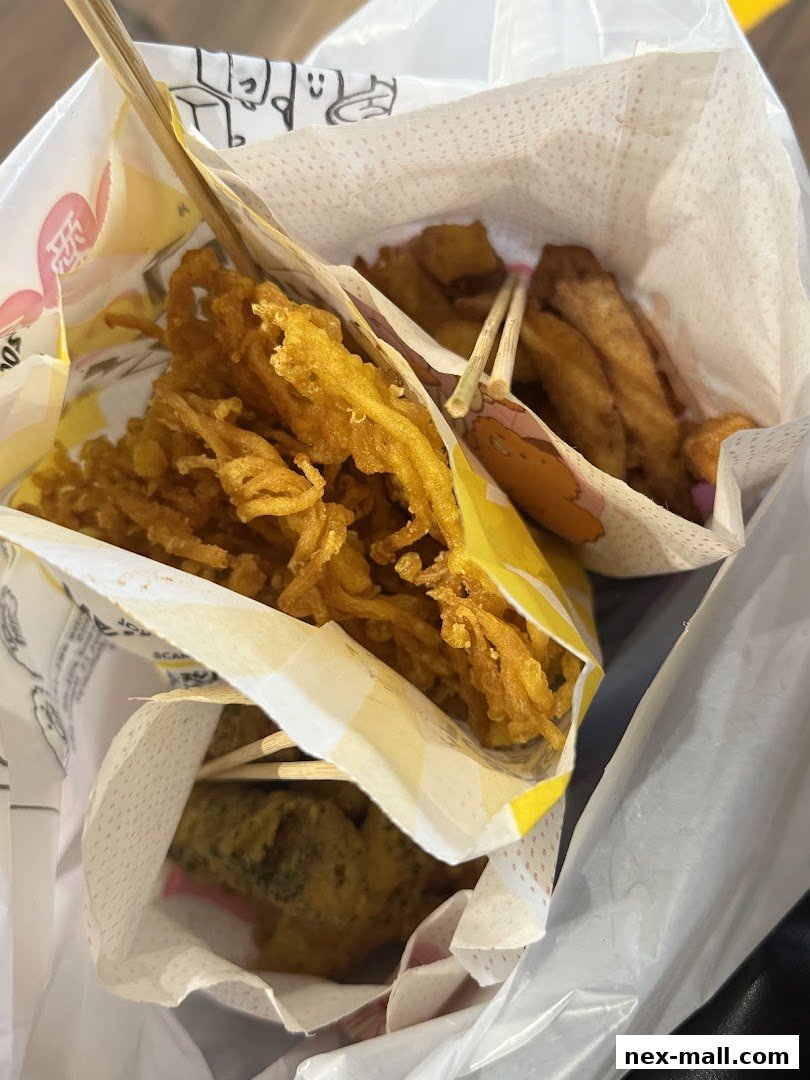 A close-up of fried enoki mushrooms and other fried snacks in paper packaging.
