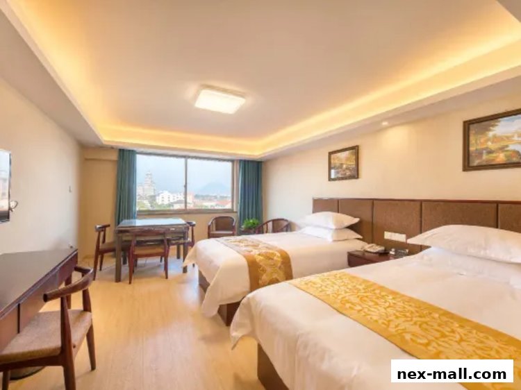 A hotel room with two beds, a desk, and a window with a city view.