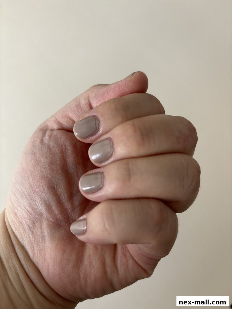 A close-up shot of a hand with neatly painted taupe-colored fingernails.