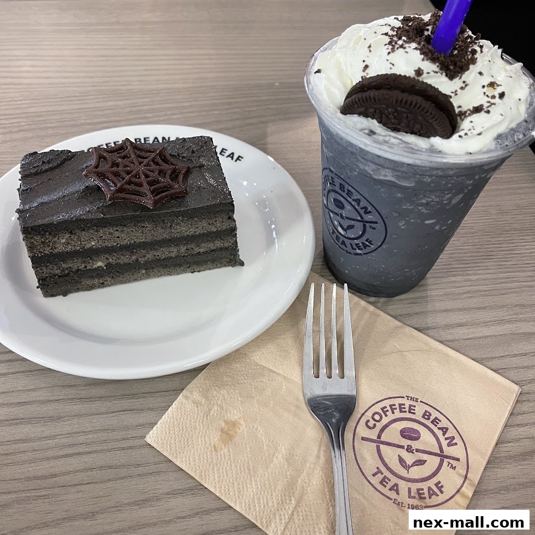 A slice of black sesame cake with a spiderweb decoration and a dark-colored drink.