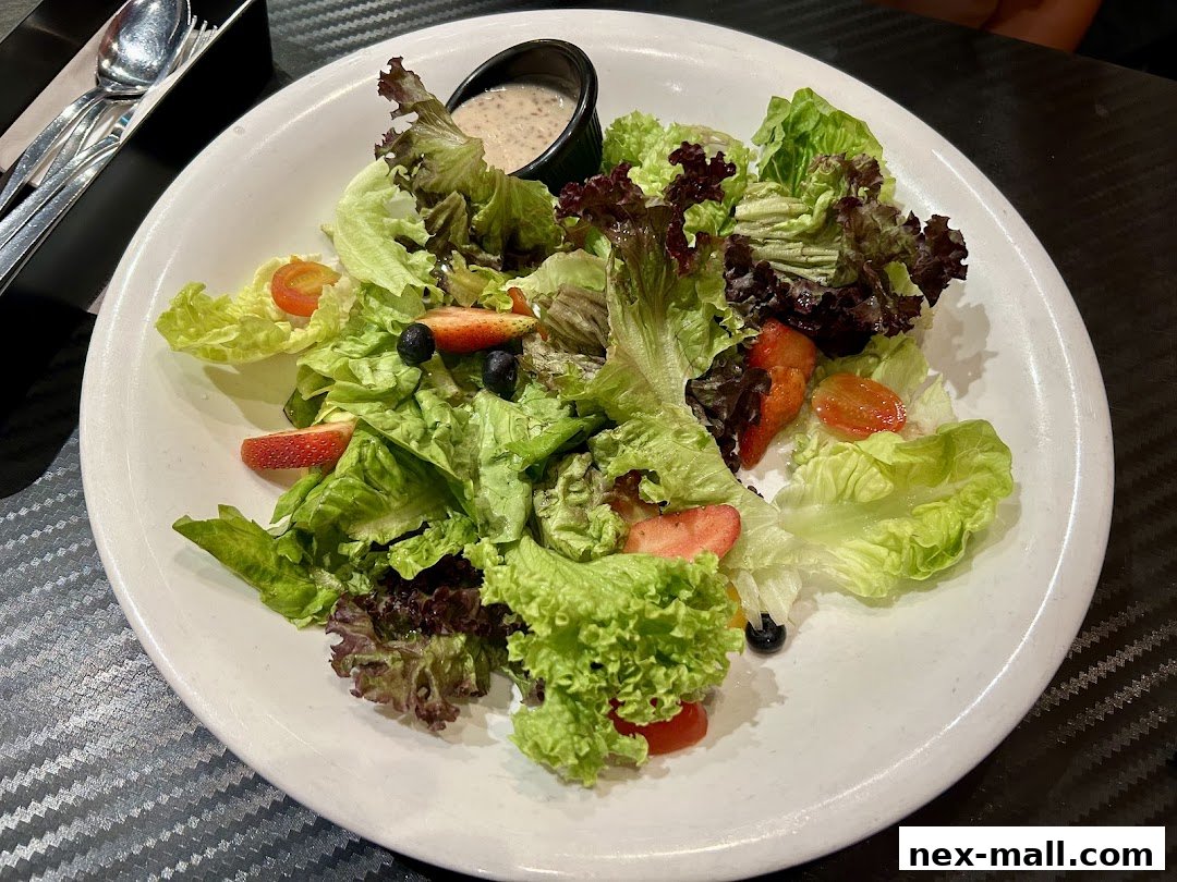A fresh salad with lettuce, strawberries, blueberries, and cherry tomatoes, served with dressing.