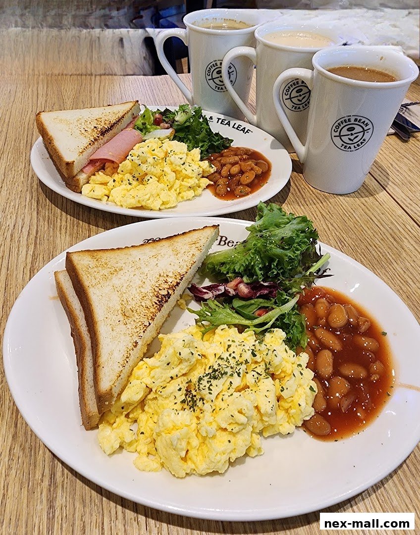 Two breakfast plates with scrambled eggs, toast, beans, and salad, plus coffee cups.
