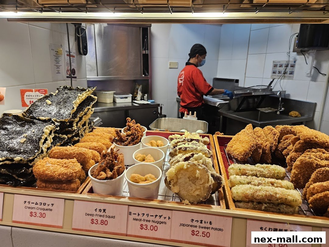 A display of various fried Japanese snacks and tempura with prices listed below.
