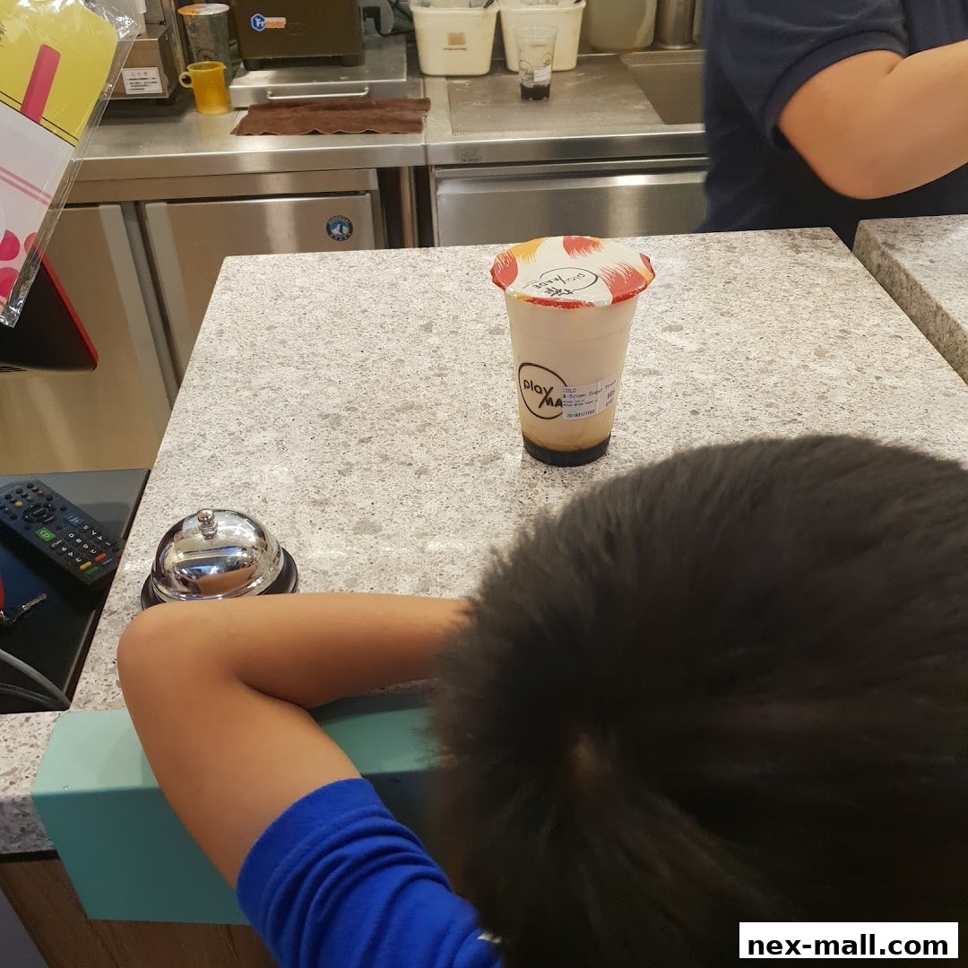 A person's arm rests on a counter next to a drink from PlayMade.