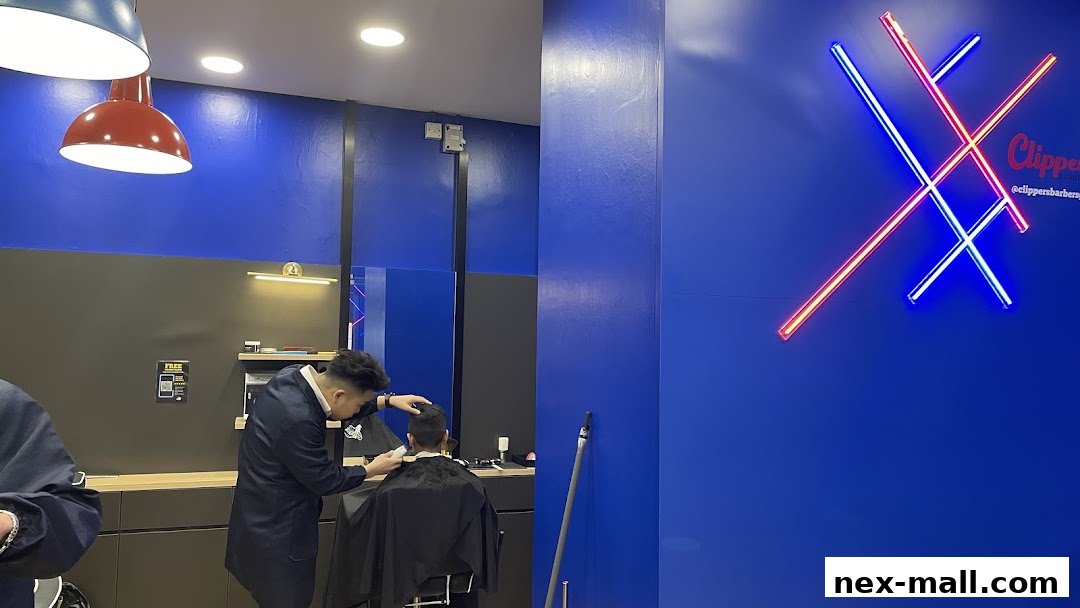 Barber cutting a client's hair in a modern shop with neon signage.