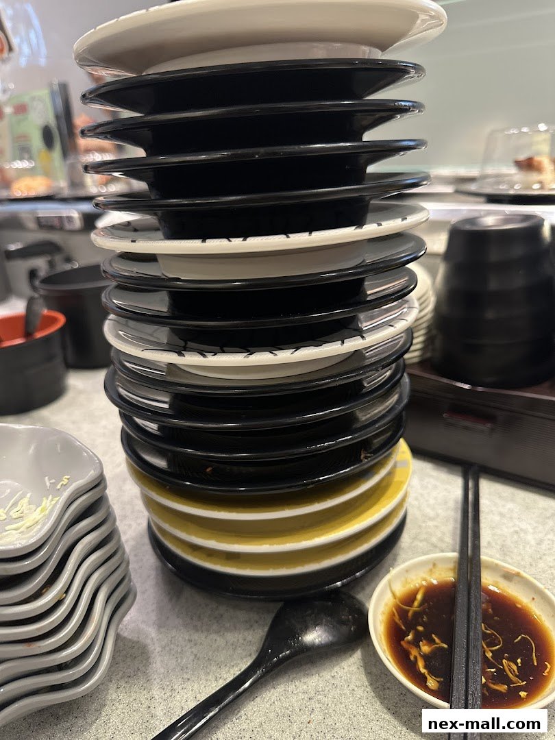 A tall stack of sushi plates, soy sauce dish, and chopsticks on a table.
