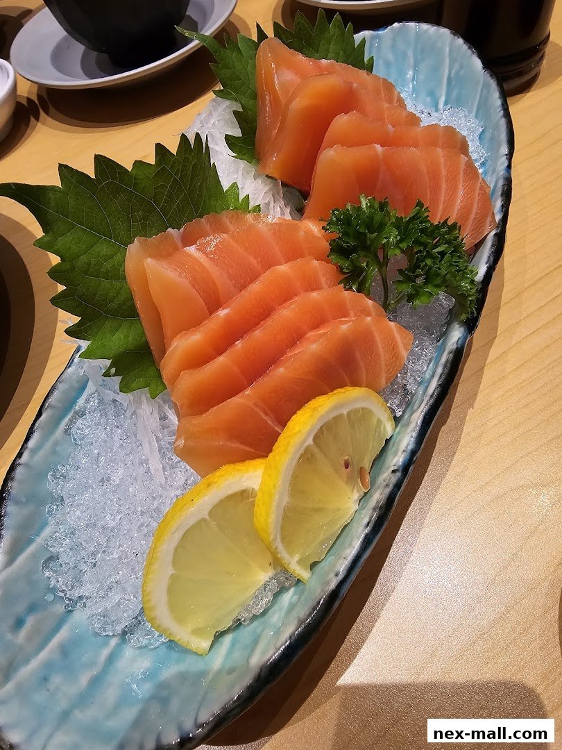 A platter of fresh salmon sashimi served with lemon slices and garnishes on ice.