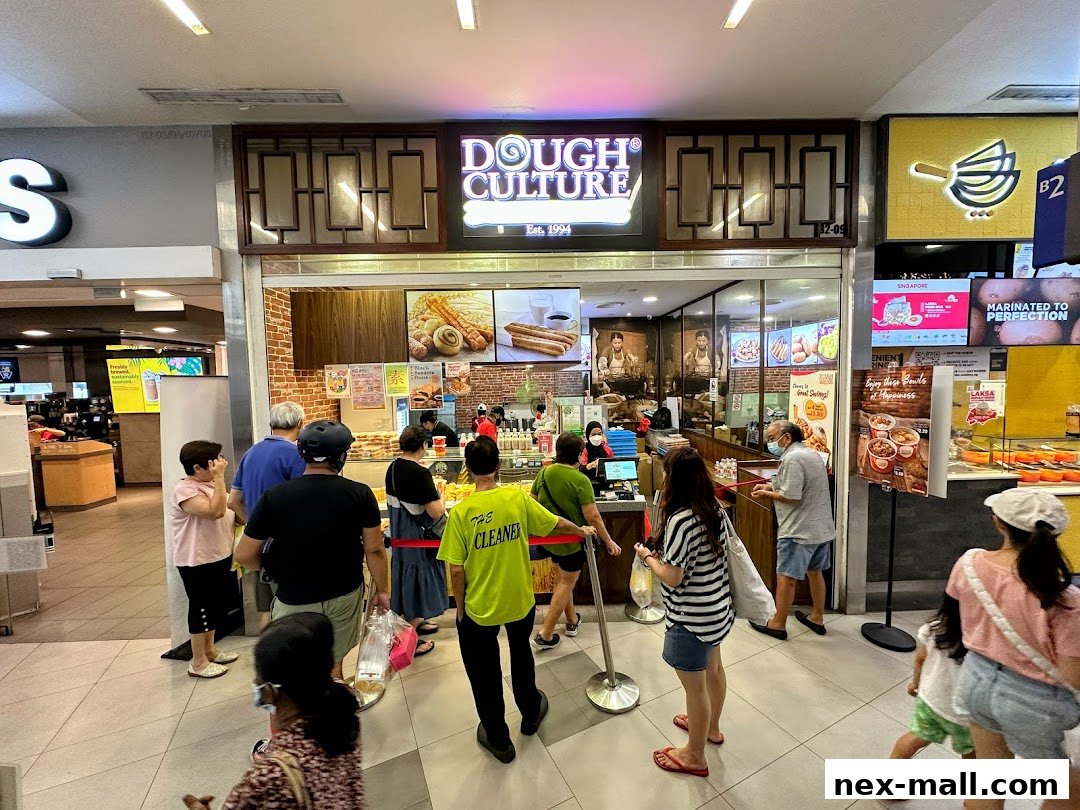 People queuing outside a Dough Culture shop with a display of baked goods and menu boards.