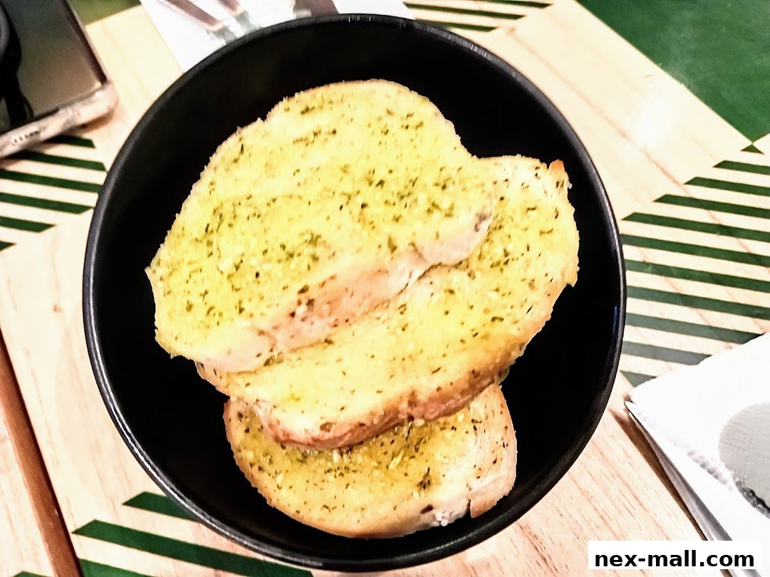 A black bowl filled with slices of garlic bread with herbs.