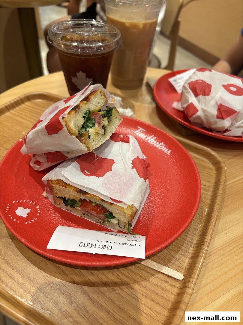A close-up of a sandwich and drinks from Tim Hortons on a red plate.