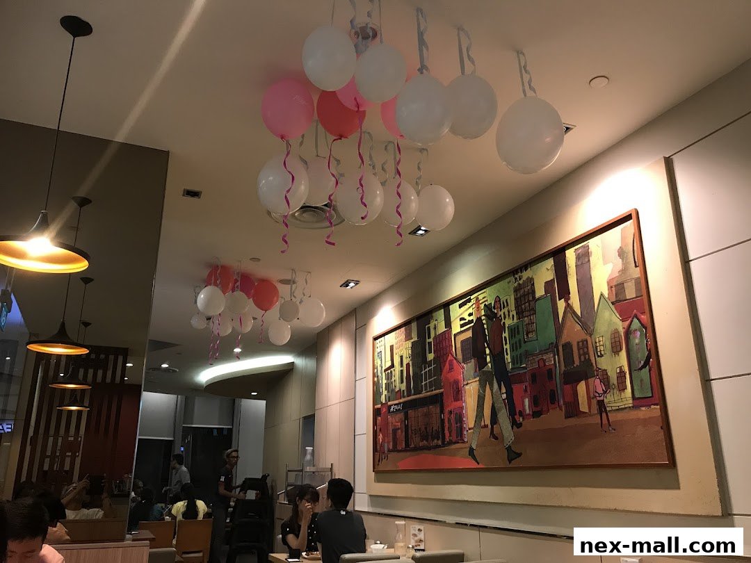 Interior of a KFC restaurant decorated with balloons and a large cityscape painting.