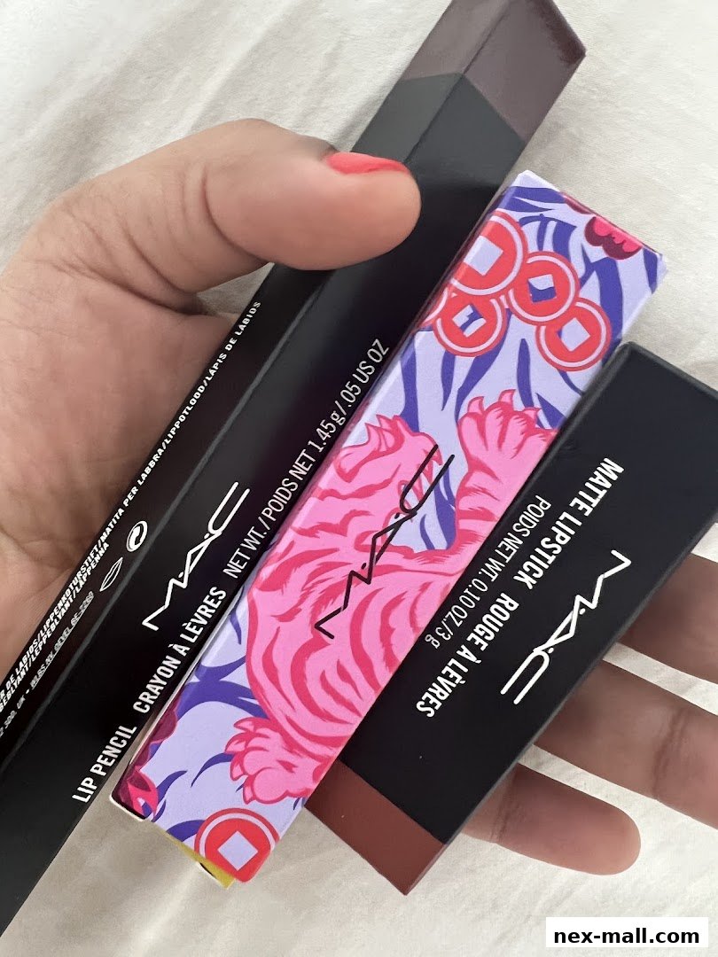 A hand holds several MAC Cosmetics makeup products, including lipsticks and a lip pencil.