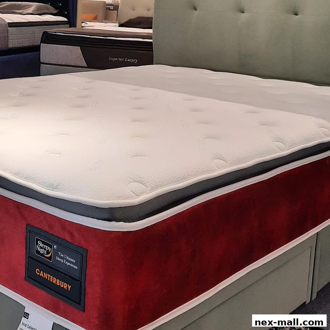 A close-up view of a plush mattress with a red side panel and a tufted headboard.