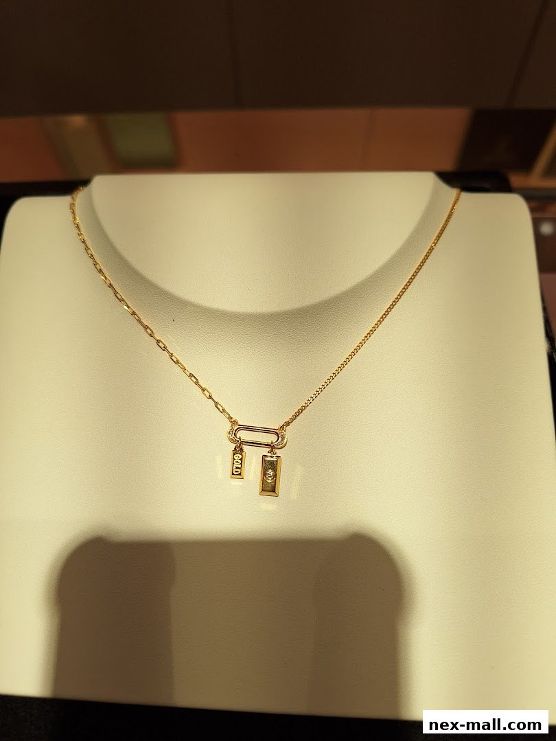 A close-up of a gold necklace with a diamond pendant displayed on a white stand.