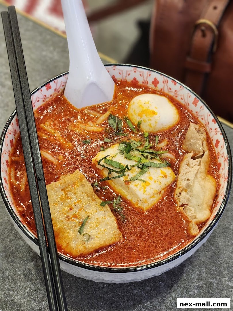 A close-up shot of a delicious bowl of Laksa with tofu, egg, and herbs.