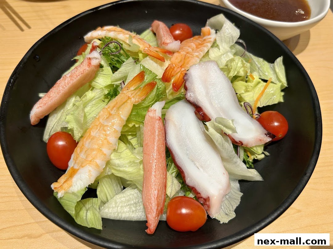 A black bowl filled with a fresh seafood salad featuring shrimp, octopus, imitation crab, and cherry tomatoes.