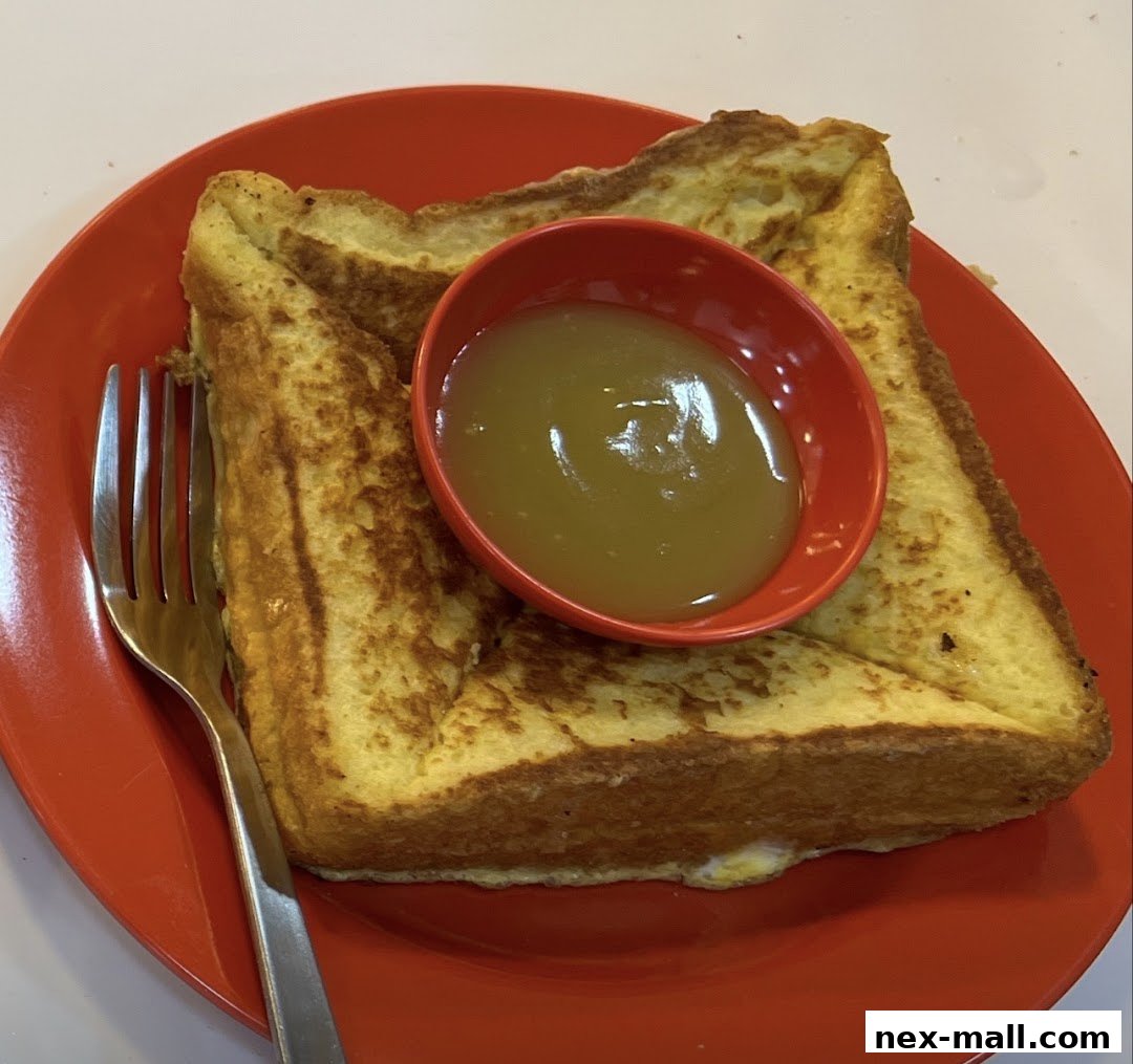 A close-up shot of French toast with kaya dip on a red plate with a fork.