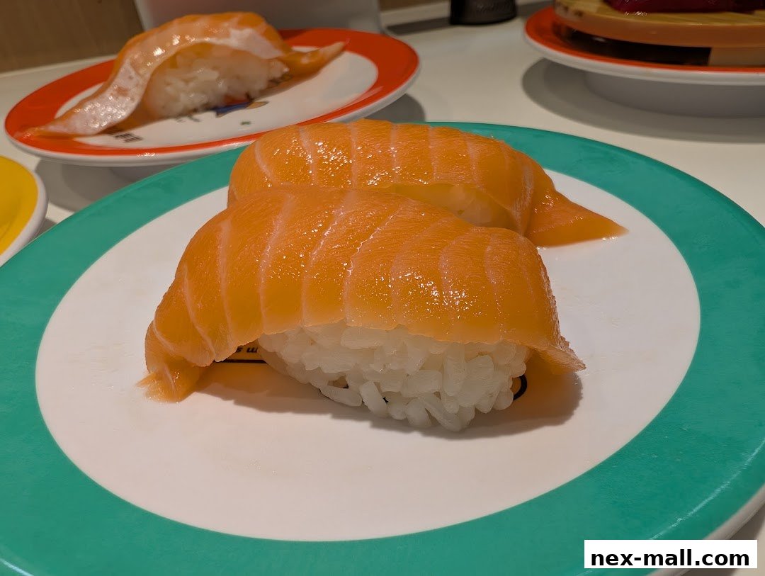 Close-up of fresh salmon sushi on plates, with more sushi in the background.