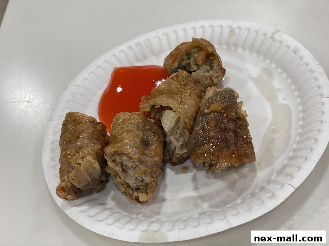 A plate of crispy fried spring rolls with a side of sweet chili sauce.