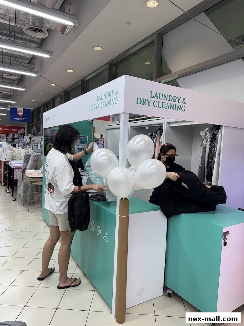 Customers interact with staff at a laundry and dry cleaning service counter.