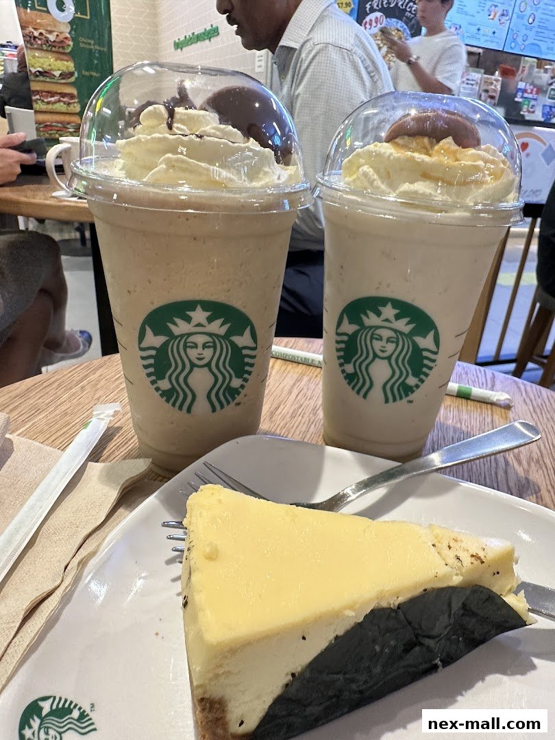 Two Starbucks Frappuccinos and a slice of cheesecake on a table.