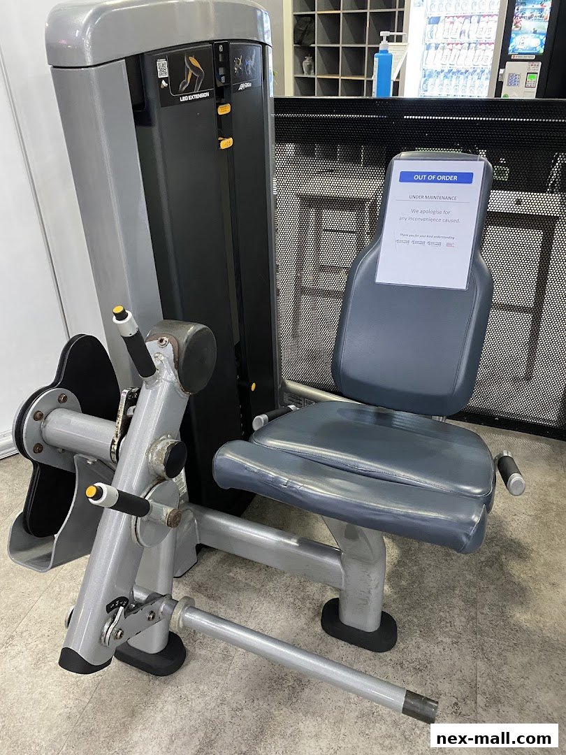 A leg extension machine in a gym with an 'Out of Order' sign.