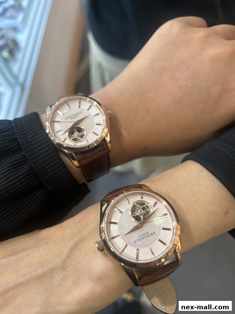 Two people wearing stylish rose gold automatic watches with white dials and brown leather straps.